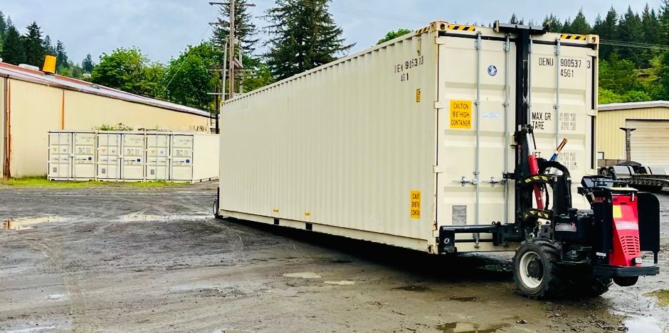 Beige shipping container being positioned by a container Mule in a gravel yard