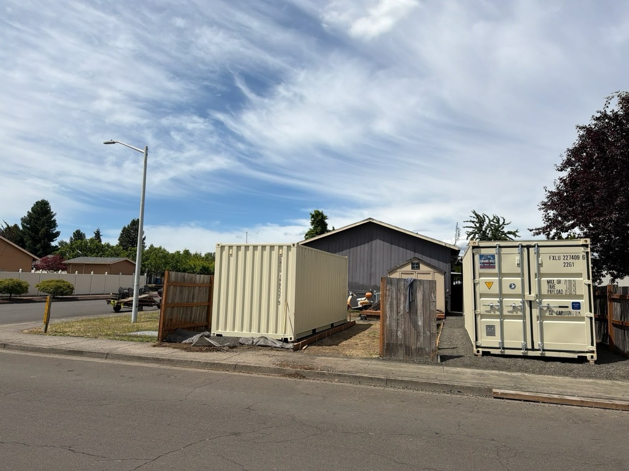 Two beige shipping containers installed beside a residential property - Grand Box Northwest